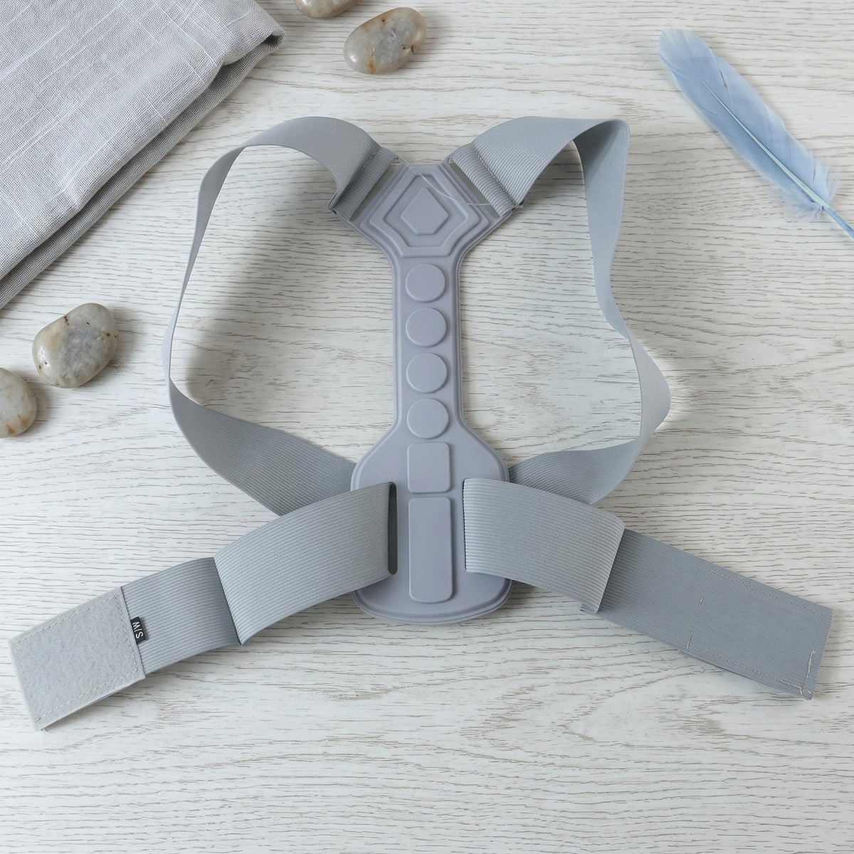 Gray posture corrector laid flat on a light wooden surface